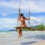 A woman sits on a swing on the White Sand Beach in Phuket