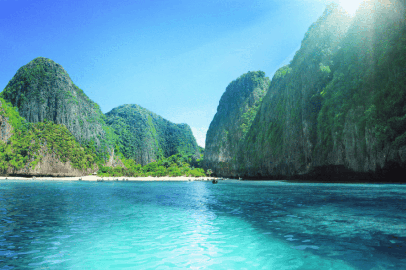 Maya Bay tropical bay with towering limestone cliffs covered in lush green vegetation.