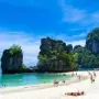 Sunny day at Krabi Island beach, people sunbathing and boats anchored offshore